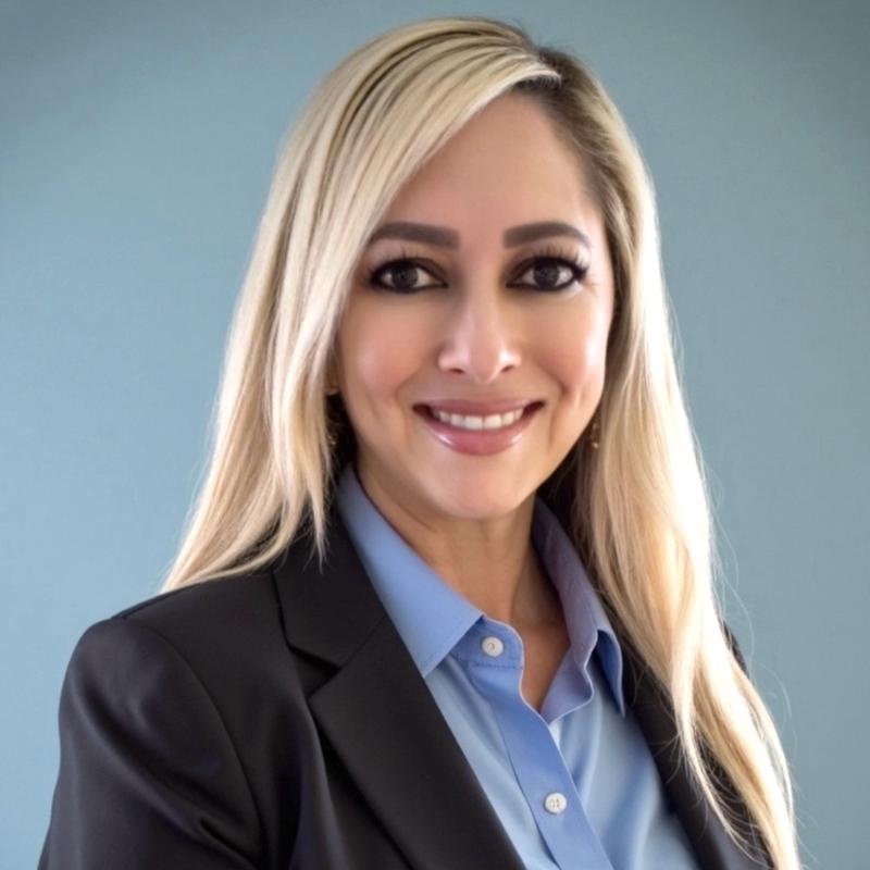 Sabrina Vargas, a North Peoria real estate agent with HomeSmart, in a professional headshot against a light blue background.